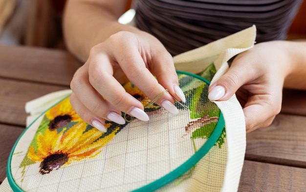 Osoba haftująca kwiaty na tkaninie